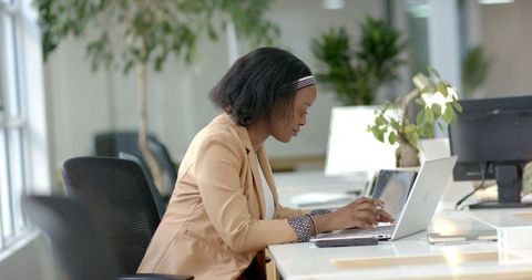 African American Businesswoman Working on Laptop in Bright Modern Open-Plan Office