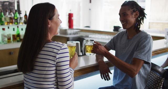 Friends enjoying beer together at a modern bar counter, engaging in casual conversation. Ideal for images promoting social gatherings, casual nightlife, and friendship bonding. Can be used in advertisements for bars, breweries, or social apps.