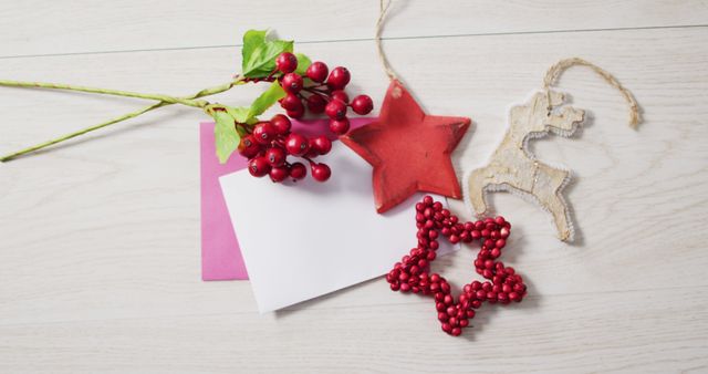 Image of christmas decorations, red berries with white and pink cards on wooden background. christmas, tradition and celebration concept.