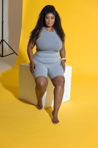 Curvy african american woman wearing grey activewear on vibrant yellow background
