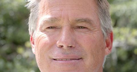 Senior Male Smiling in Sunlit Garden Scenery