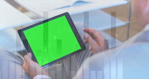 Man analyzing data on green screen tablet with overlay charts