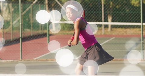 Young woman preparing backhand on outdoor tennis court in pink top and black skirt action