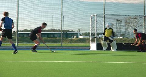 Male Field Hockey Players Competing Near Goal on Synthetic Turf