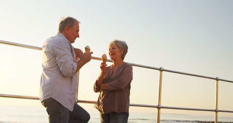 Senior couple enjoying ice cream by sea