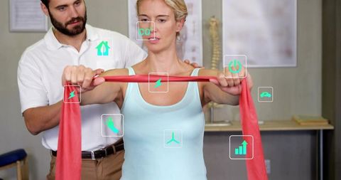 Woman performing resistance band shoulder rehab while clinician providing guided support