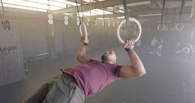 Man exercising on gymnastic rings in industrial gym - Download Free Stock Images Pikwizard.com