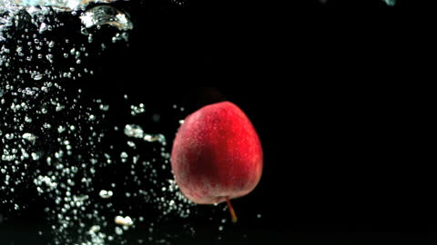 Red Apple Submerged in Water With Bubbles Against Black