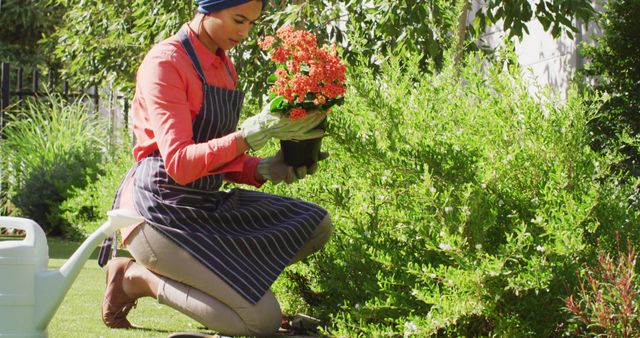 Image of biracial woman in hijab planting flowers in garden. Lifestyle and spending free time at home and garden concept.