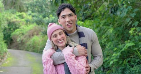 Smiling couple hugging on leafy park path during cozy outdoor walk