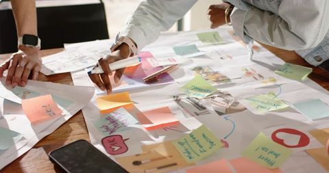 Diverse team brainstorming over colorful sticky notes and sketches on wooden table
