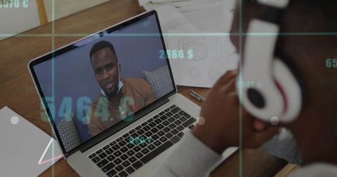Connecting over video call on laptop with headphones and workspace notes