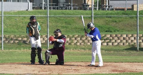 Young baseball batter poised at home plate with catcher and umpire