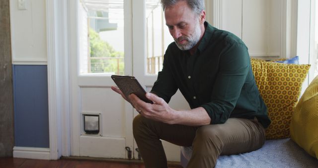 Middle-aged man reading tablet on modern sofa indoors - Download Free Stock Images Pikwizard.com