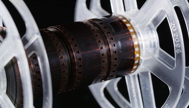 Rotating vintage motion-picture filmstrip winding on clear plastic reel macro closeup