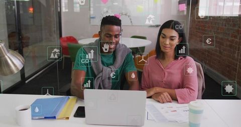 Young coworkers collaborating on sustainability analytics with transparent data overlays