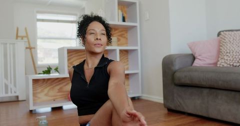 African american woman stretching at home doing seated spinal twist yoga in living room