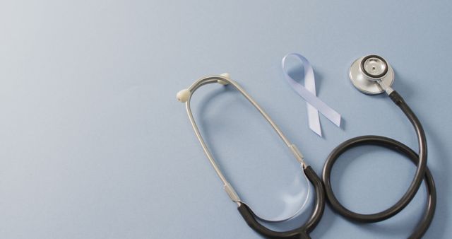 Image of stethoscope and pale blue prostate cancer ribbon on pale blue background. medical and healthcare awareness support campaign symbol for prostate cancer.