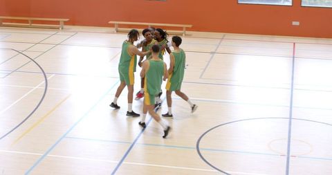 Diverse basketball team huddling on indoor court