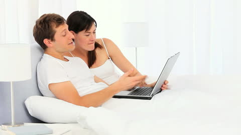Couple Relaxing in Bed Using Laptop for Leisure Activity