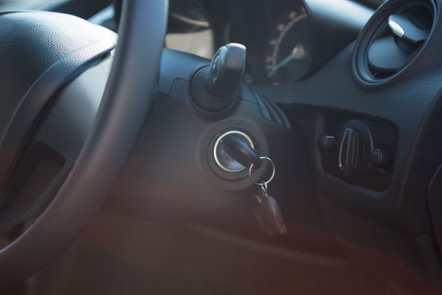 This image shows a close-up view of a car's interior, focusing on the steering wheel and a key inserted in the ignition. Ideal for use in automotive advertisements, driving safety campaigns, car rental services, and articles related to vehicle maintenance or driving tips.