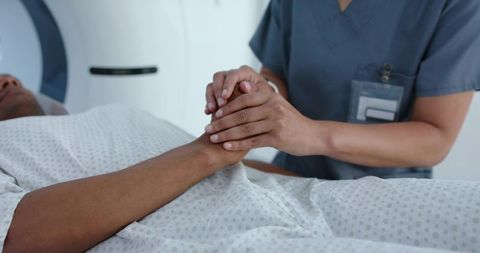 Nurse holding male patient hand during mri scan providing comfort and reassurance