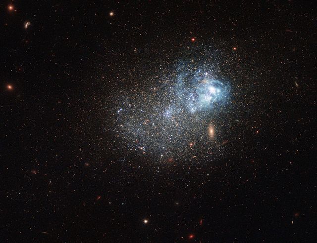Markarian 209, an ancient yet star-studded blue compact dwarf galaxy, is depicted with vibrant blue star-forming regions. This image, captured by the Hubble Space Telescope, includes data across ultraviolet, visible, and infrared wavelengths. Ideal for educational materials, astronomical presentations, and inspiring backdrop for space-themed media.