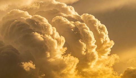 Golden cumulonimbus clouds glowing at sunrise with sunbeams and dramatic texture