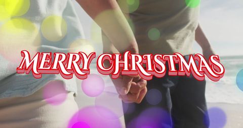 Merry Christmas Message over Couple Holding Hands at Beach