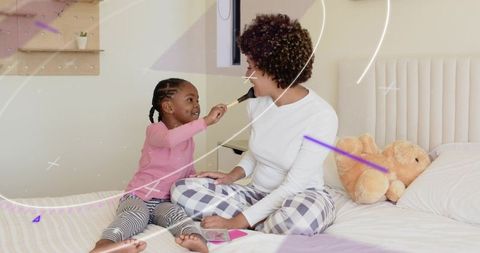 Little girl brushing mother's face on bed sharing playful morning bonding moment
