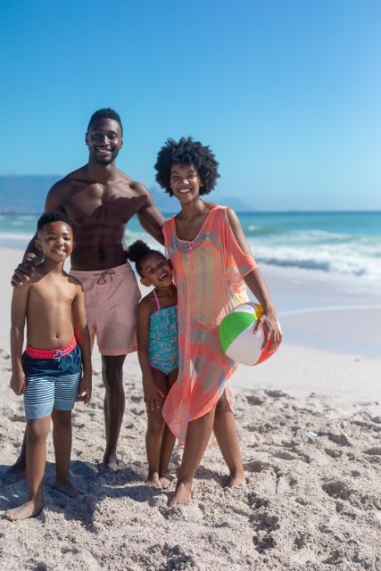 Portrait of smiling african american family enjoying summer weekend together at beach on sunny day. unaltered, family, lifestyle, togetherness, enjoyment and holiday concept.