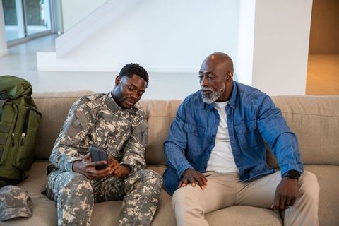 Military Son Showing Phone to Father on Comfortable Sofa