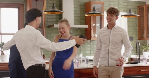 Young friends laughing and greeting at kitchen island with smartphone and blue dress