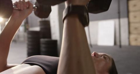 Athletic Woman Performing Dumbbell Chest Press at Gym