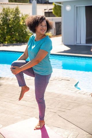 Woman Practicing Outdoor Yoga by Pool on Sunny Day