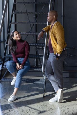 Diverse couple chatting on industrial metal staircase in modern loft wearing maroon tops