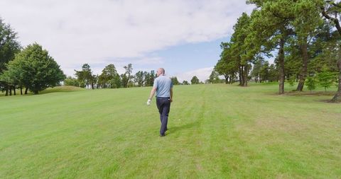 Senior golfer strolling through scenic fairway on sunny day