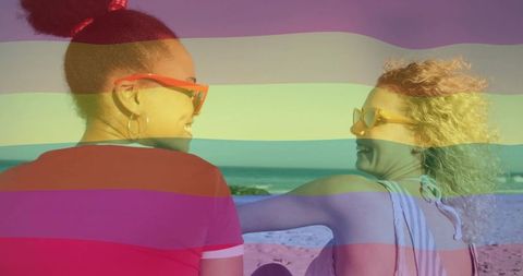 Laughing friends enjoying sunny beach with rainbow overlay and sunglasses