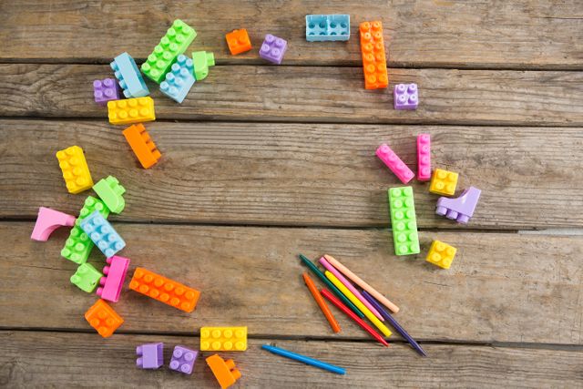 Colorful toy blocks and crayons scattered on a wooden table, perfect for illustrating children's creativity and playtime. Ideal for educational materials, parenting blogs, and advertisements for children's toys or art supplies.