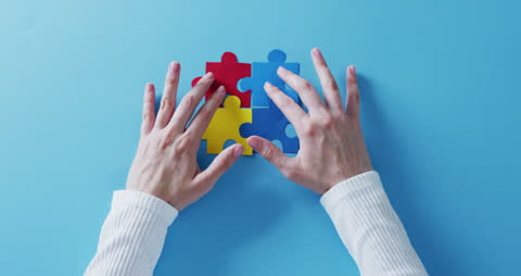 Hands Solving Colorful Puzzle on Blue Surface
