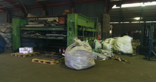 A cluttered recycling facility interior, with materials scattered. Piles of recyclables await sorting and processing in this industrial setting, highlighting waste management challenges.