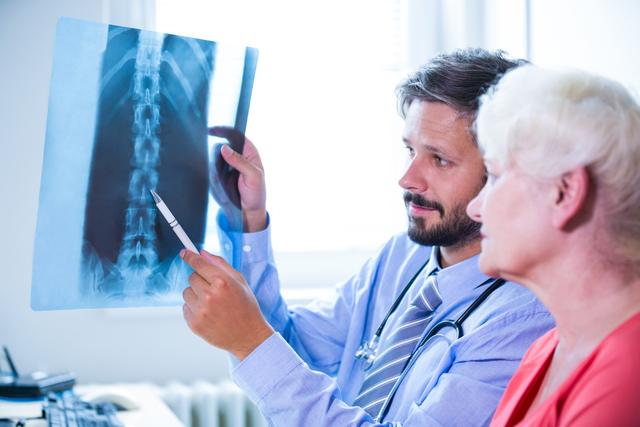 Doctor explaining x-ray results to elderly patient in hospital. Useful for healthcare, medical consultation, patient care, senior health, and medical advice themes.