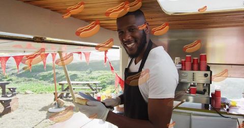 Smiling street food vendor serving hot dog at outdoor food truck window