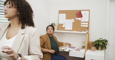 Female designers collaborating in bright studio workspace sketching moodboard and plans
