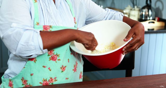 African American Woman Mixing Ingredients in Kitchen with Floral Apron - Download Free Stock Images Pikwizard.com