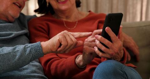 Senior Couple Relaxing, Sharing Moments on Smartphone in Cozy Living Room