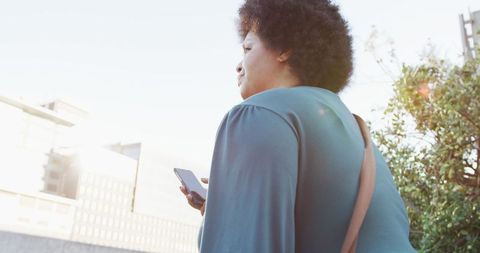 Confident Plus-size Woman Walking with Smartphone in Urban Setting