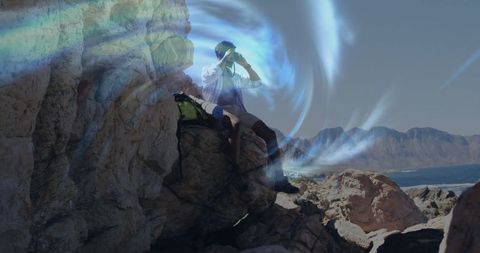 Adventurous hiker on rocky cliff scanning ocean horizon