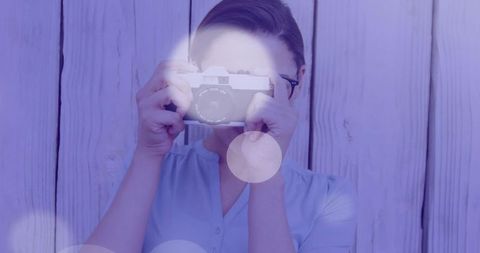 Vintage Female Photographer Using Film Camera Against Wooden Wall