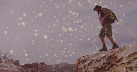 Hiker Exploring Mountain Outcrops with Eerie Light Particles
